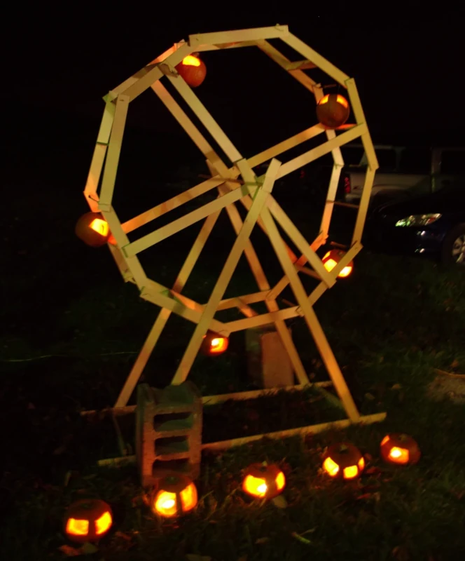 A wooden ferris wheel with pumpkins as the cars.