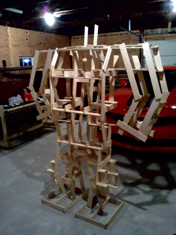 The wooden skeleton standing in front of a car and a piano in my garage.