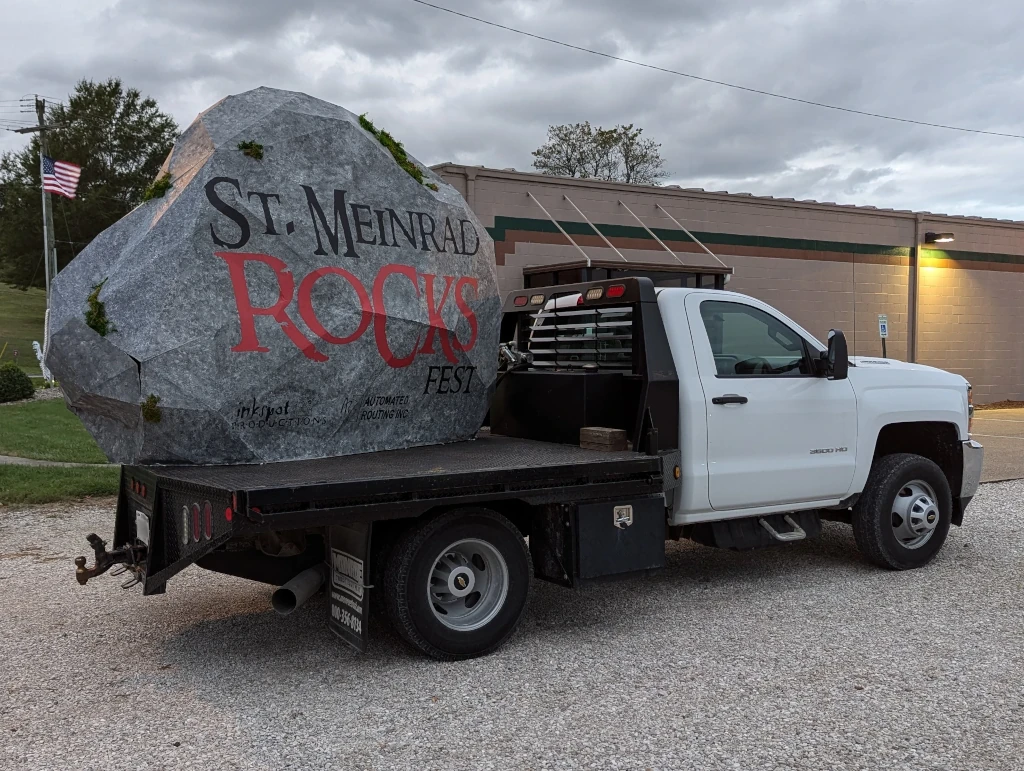 The painted cardboard rock sitting on the bed of a truck.