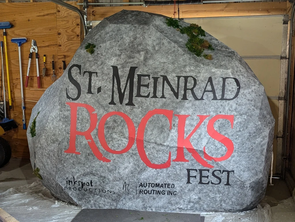 An eight-foot-tall rock, made of cardboard that’s been painted a mottled gray with the name of a music festival and its sponsors.